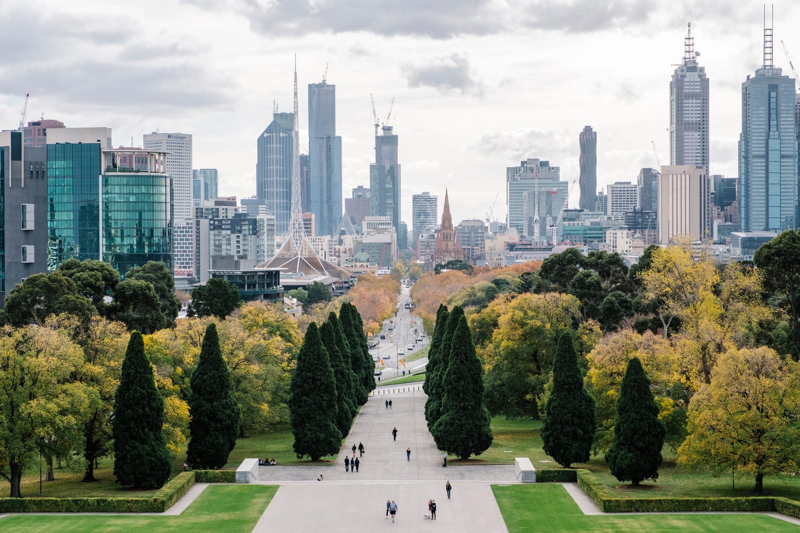 Melbourne's skyline seen from the Shrine of Remembrance, down a tree-lined avenue past the Arts Centre spire