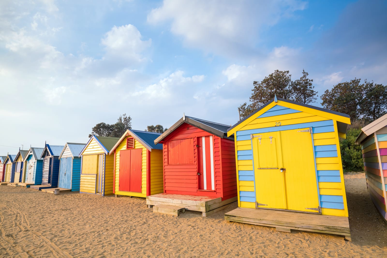 Brightly painted bathing boxes in a row on the sand at Brighton Beach